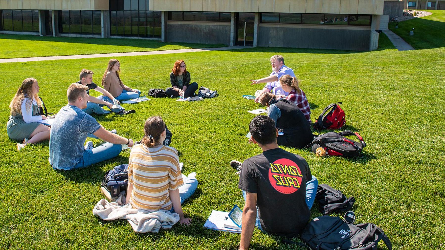 A professor teaching a class outside on the lawn.